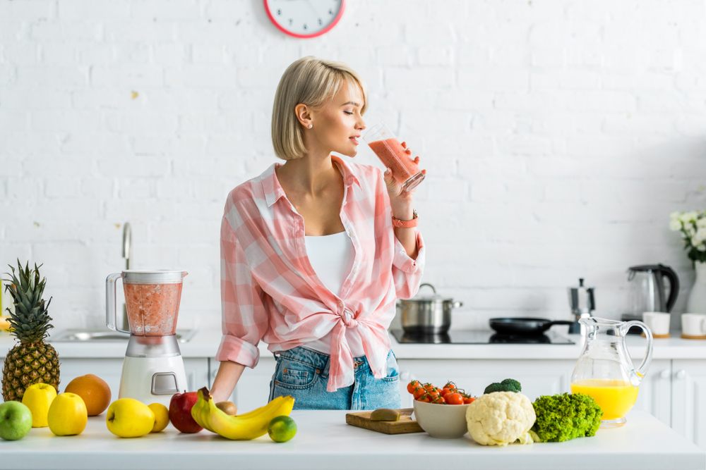 ženska pije smoothie v kuhinji